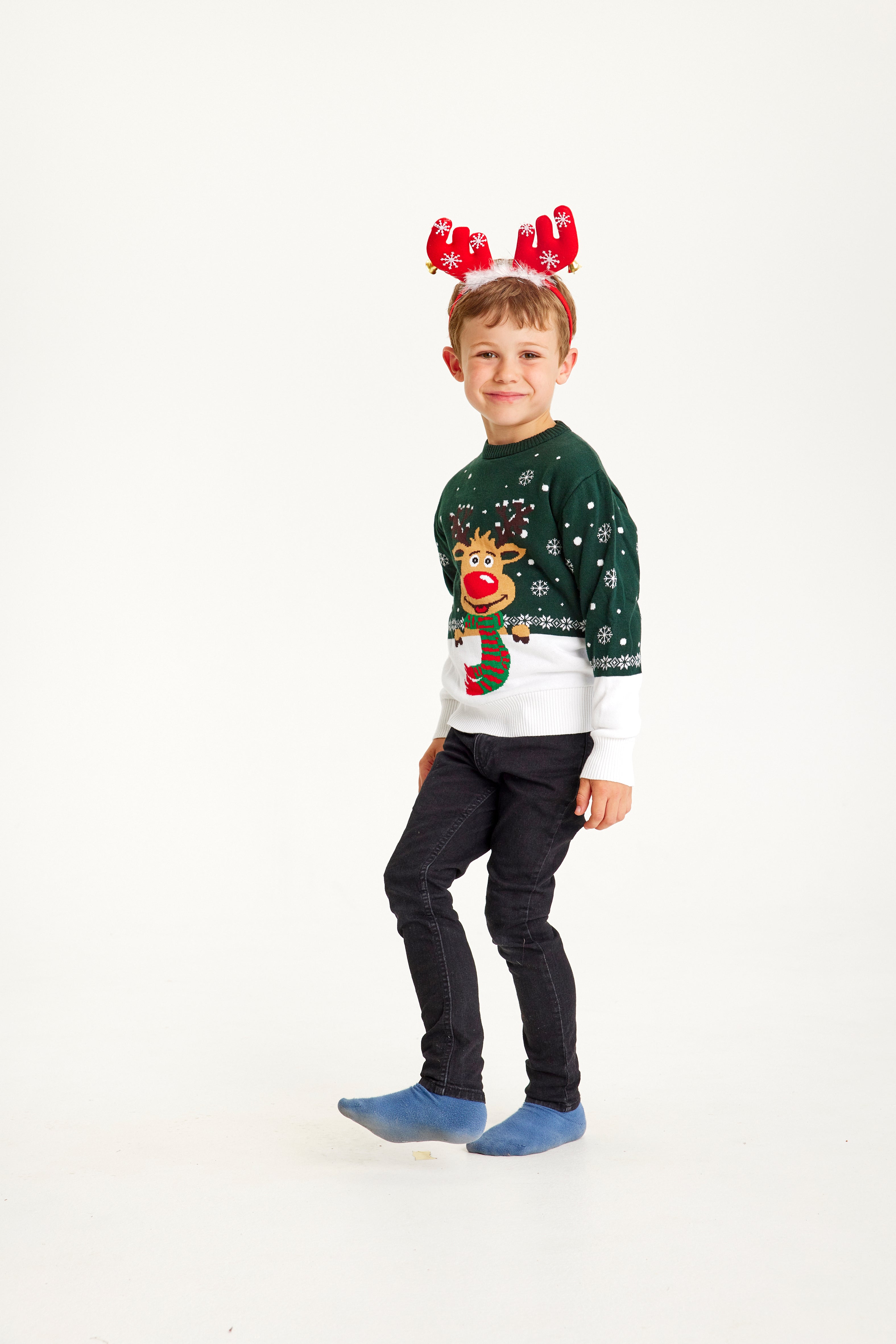 Et barn iført røde rensdyrgevir iført en grøn julesweater med Rudolf på.